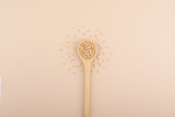 A minimalistic wooden spoon with brown rice. Top view