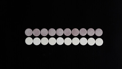 round cylinders close-up on a black background pills, vitamins, eye shadow in a row 10 circles