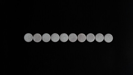 round cylinders close-up on a black background pills, vitamins, eye shadow in a row 10 circles