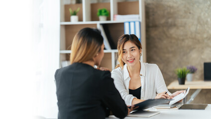 Two business woman check report before presentation to customer, Business women at office desk working together on a laptop, teamwork concept.
