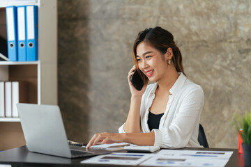 Portrait of happy lady typing in mobile while locating at desk in office, Young business woman on the phone at office.