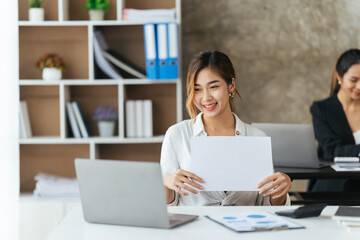 Beautiful young woman using laptop and smiling while working in office, business concept.