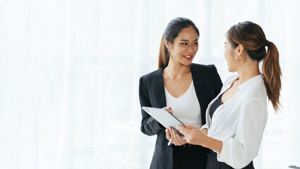 Smiling businesswoman talking with partner while standing in modern office interior, team of...