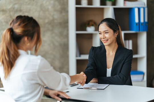 Two Businesswomen Shaking Hands In Modern Office, success business people shake hands.