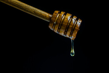 Honey dripping to a honey dipper isolated on a black background.  Concept healthy food.