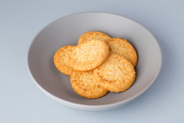Minimalism. Yellow cookies in a gray plate on a gray background. Close-up. View from above. A place to copy.