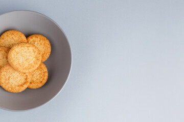 Minimalism. Yellow cookies in a gray plate on a gray background. Close-up. View from above. A place to copy.