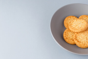 Minimalism. Yellow cookies in a gray plate on a gray background. Close-up. View from above. A place to copy.