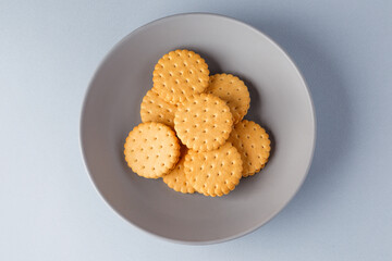 Minimalism. Yellow cookies with fruit filling on a gray background in a gray plate. Light background. Close-up in the center. View from above. A place to copy.