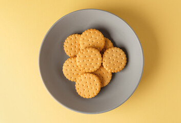 Minimalism. Yellow cookies  with fruit filling on a yellow background in a gray plate. Light background. Close-up in the center. View from above. A place to copy.