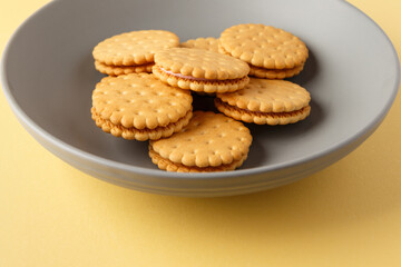 Minimalism. Yellow cookies  with fruit filling on a yellow background in a gray plate. Light background. Close-up in the center. Side view. A place to copy.