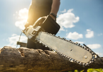 Close-up of a man sawing a log with a chainsaw