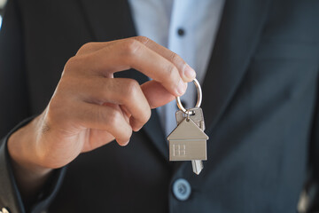 Close up view realtor broker holding home keychain in his hand.