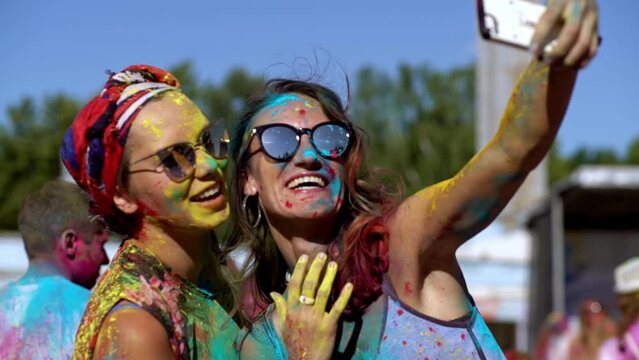 Young girls pose and smile for a selfie at the Holi festival of colors