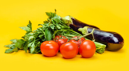 Ripe tomatoes, parsley and eggplant on a yellow background