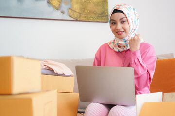 Young Asian Muslim businesswoman selling online products. Start-up business at home.