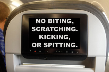 Humorous interior plane TV monitor message prohibiting passengers from rude and unruly behavior. 
