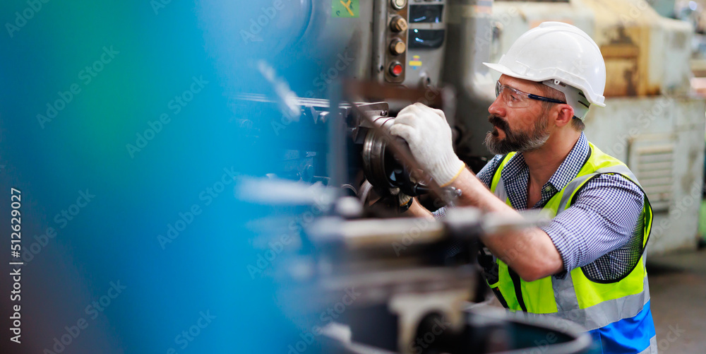 Wall mural caucasian or hispanic latin man worker wearing safety goggles control lathe machine to drill compone