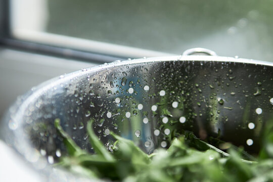 Metal colander in drops of water. Kitchenware 