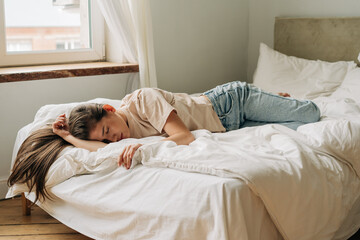 Depressed frustrated young woman is sad lying on the bed during the day.