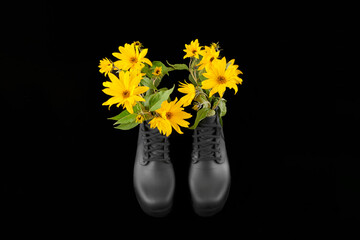 Black women platform boots with bouquet of yellow Jerusalem artichoke flowers, black background