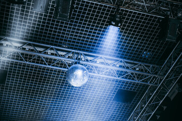 Silver mirror disco ball in the rays of the spotlights
