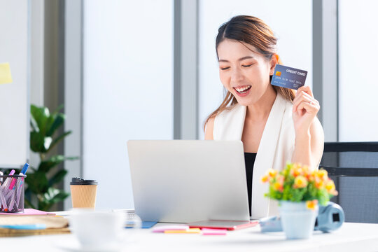 Asian businesswoman using her credit card to shop online at her company office