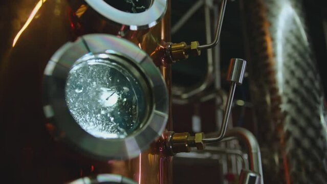 Hot water , liquid boiling inside distillery or filtration tank . Alcohol drink factory or physical experiment laboratory . Cooper or metal machine . Hot temperature , high pressure . Close up