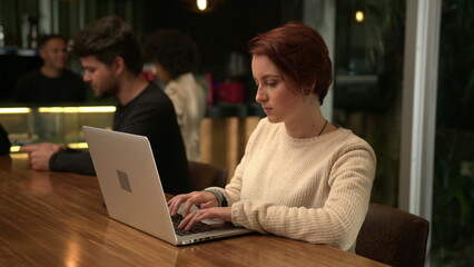 Young woman opening laptop at coffee shop working remotely. Person typing on computer at cafe