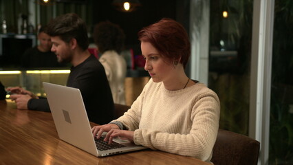 Young woman opening laptop at coffee shop working remotely. Person typing on computer at cafe