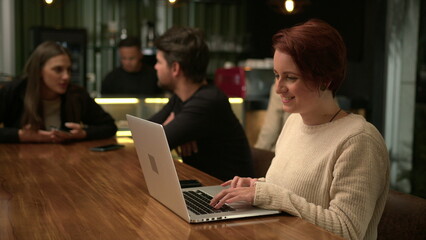 One happy millennial woman using laptop computer at cafe smiling browsing receiving positive notification