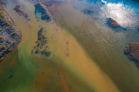 Acid rivers flowing from an industrial copper mine pollute the environment. Orange soil is contaminated with heavy metals from an industrial plant. Aerial view.