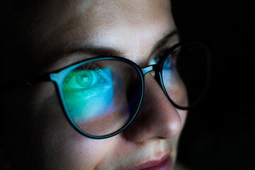 Girl works on internet. Reflection at the glasses from laptop. Close up of woman's eyes with black...