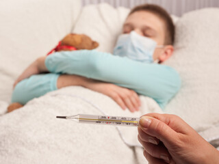 thermometer in the hand of a nurse on the background of a sick boy