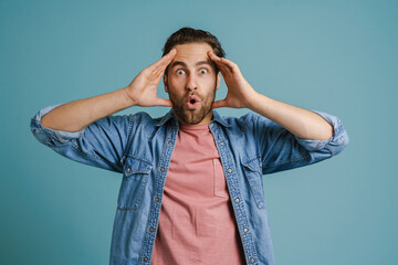 Young white man wearing shirt expressing surprise at camera