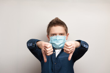 european boy with medical mask on face shows dislike