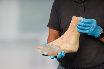 Close-up of hands of orthopedic shoemaker controlling an individual wooden last 