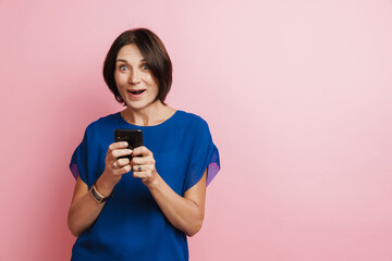Mature woman expressing surprise and using mobile phon