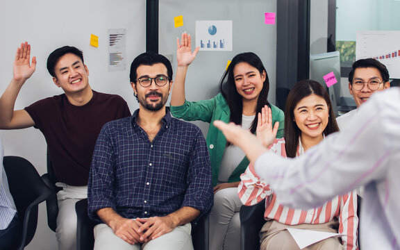 Selective focus on caucasian beard working man wearing eyeglasses, business shirt, doing workshop in indoor seminar room and smiling with happiness, pride and success, surrounded by colleagues.