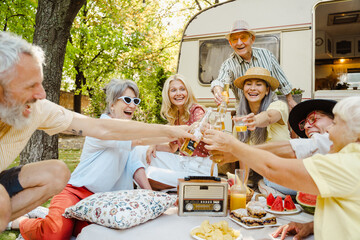 Multiracial friends smiling and drinking bear during picnic on summer day