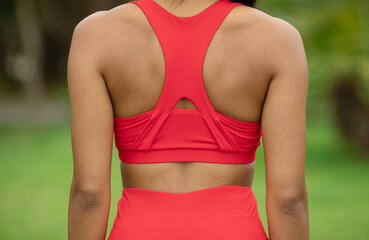 Fototapeta premium Back view of female runner taking a break, standing outdoor.