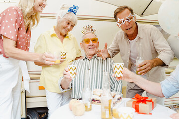 Senior man celebrating his birthday during picnic with his friends