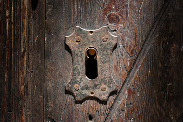 Antique keyhole of an old lock on a wooden background.  Concept and idea on the topic of security, history, protection, guard, secret etc. Rusty lock and keyhole  in a wooden door.