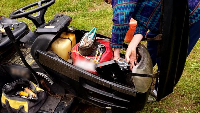 Working on carburetor in old tractor lawnmower after some breakdown in machine.