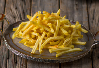 potato fries served in a dish side view on wooden table background