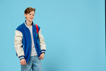 Naklejka premium student with a backpack on his shoulder posing on a blue background