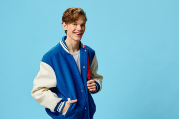 a handsome happy guy student in a fashionable bomber jacket and with a backpack on his shoulder...