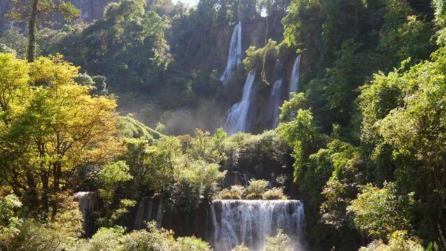 Incredibly beautiful and magical waterfall in tropical jungle at sunset in sunlight. Sunbeam shines into camera Thi Lo Su Waterfall or Thee Lor Sue in Thailand. Cascading waterfall at exotic forest