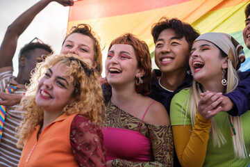 Group of teenagers carrying an lgtbi flag and fighting together