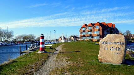 schöner Urlaubsort Orth in Fehmarn am Hafen mit grüner Wiese und dekorativem kleinen  Leuchtturm